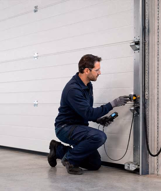 Técnico realizando el mantenimiento preventivo de una puerta industrial automática
