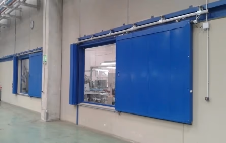 Puertas enrollables de color azul para uso industrial en fábrica.